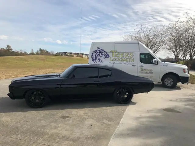 A Tigers Locksmith van parked beside a customer's classic black car on a Baton Rouge job